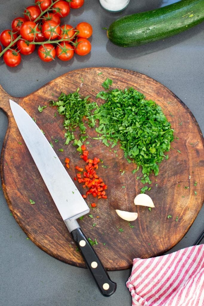 chopped herbs and chilli with garlic for chimichurri on wooden board 
