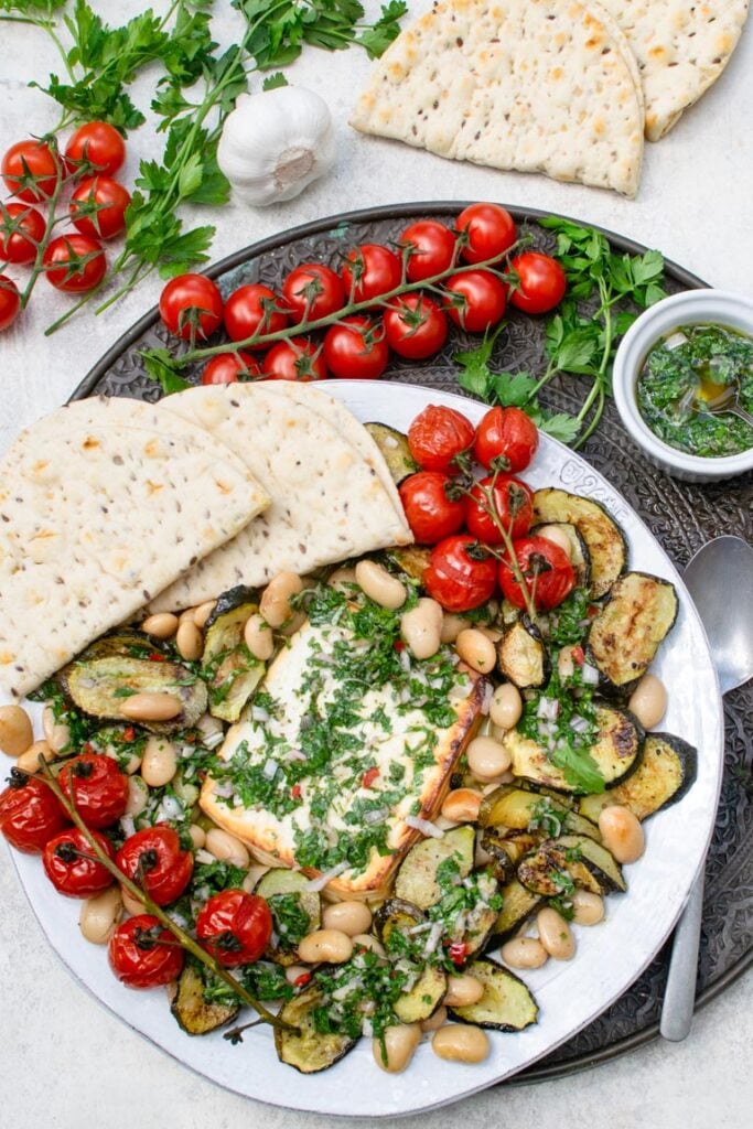 Baked feta with courgettes, butter beans and chimichurri served with flatbreads