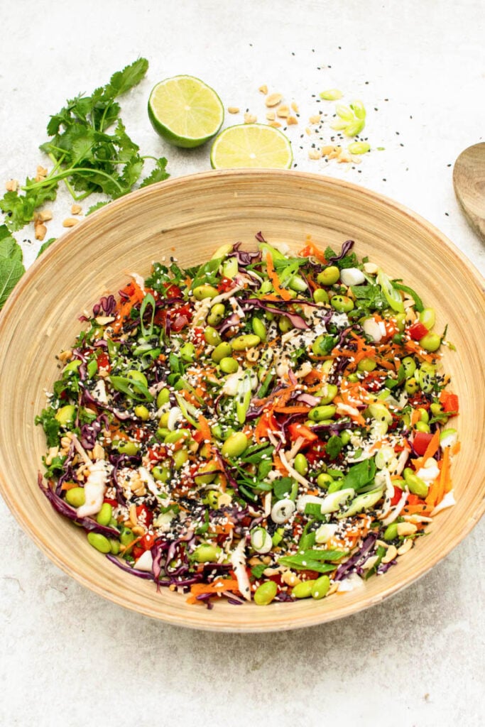 Edamame salad with shredded red cabbage, carrots, peppers, and sesame seeds in a wooden bowl