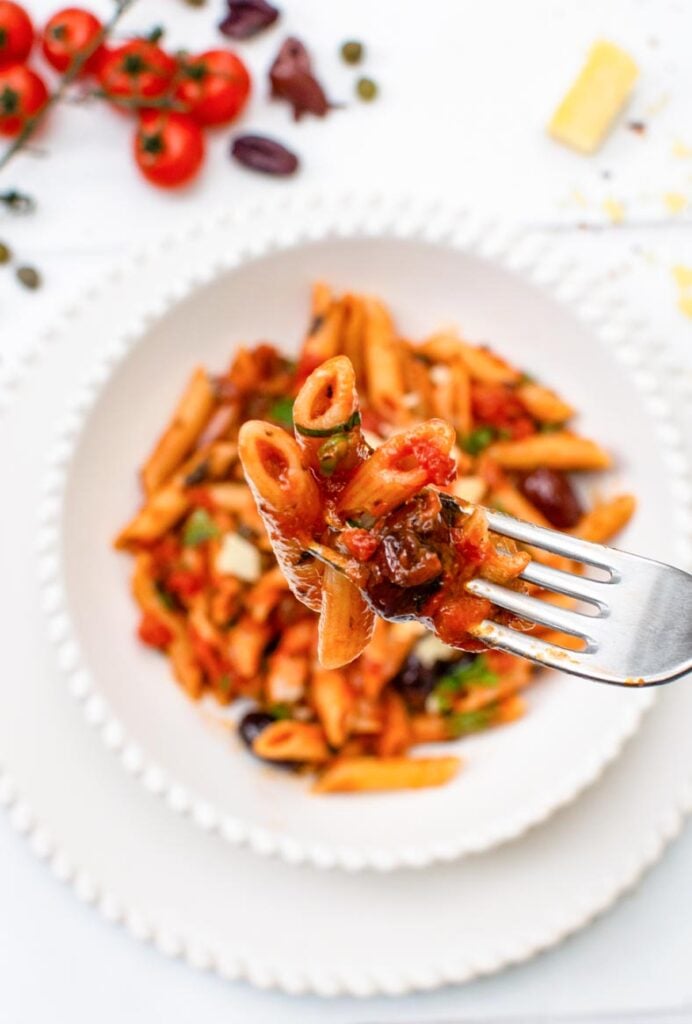 Close-up of vegan penne puttanesca with tomato sauce, olives and capers