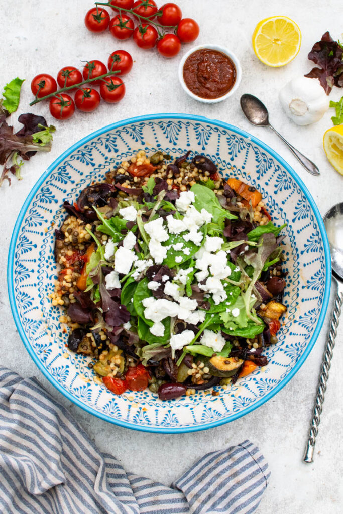 Mediterranean pearl couscous salad with salad leaves and feta