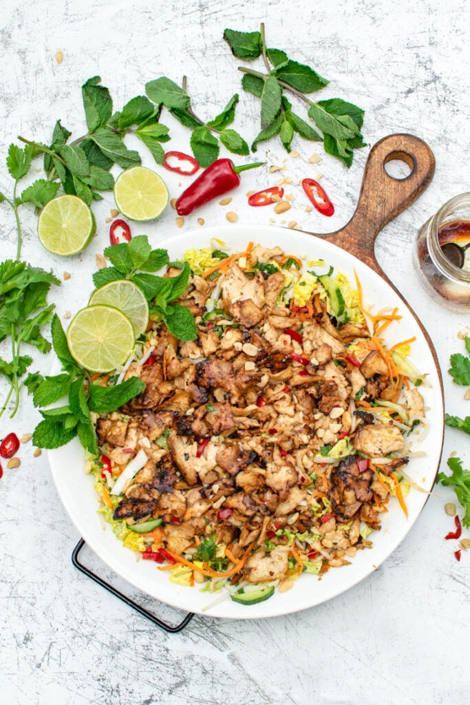 Vietnamese salad topped with baked tofu strips, fresh mint, and peanuts on a white platter
