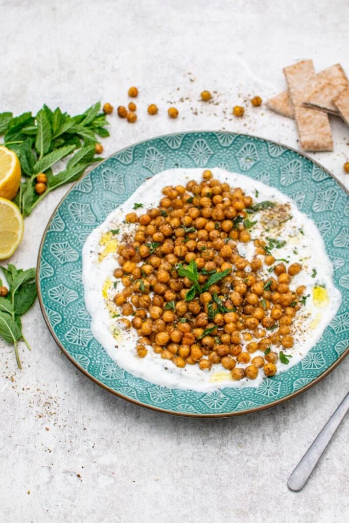 Roasted chickpeas on a bed of yogurt sauce with fresh mint and pita bread