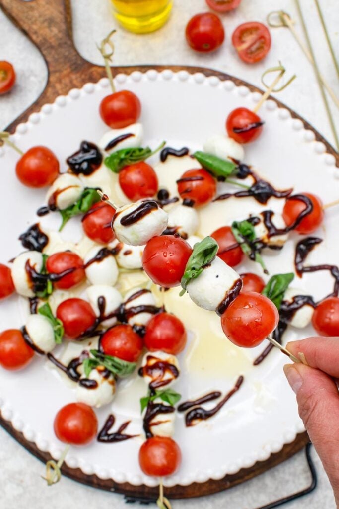 Caprese skewers with cherry tomatoes, mozzarella, and basil drizzled with balsamic glaze