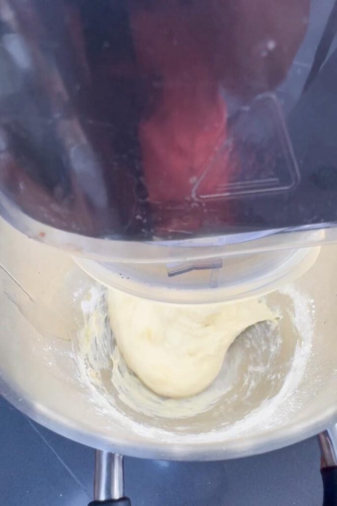 Smooth, pale dough being kneaded in a metal food processor bowl