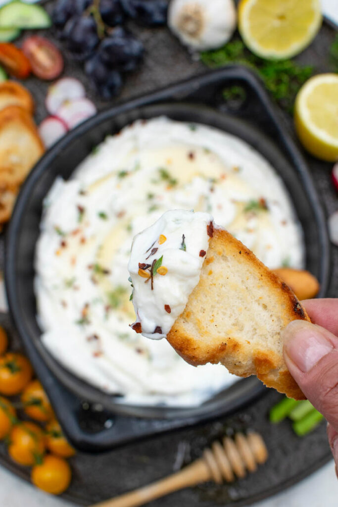 Toasted bread topped with creamy whipped feta dip, red pepper flakes, and fresh herbs