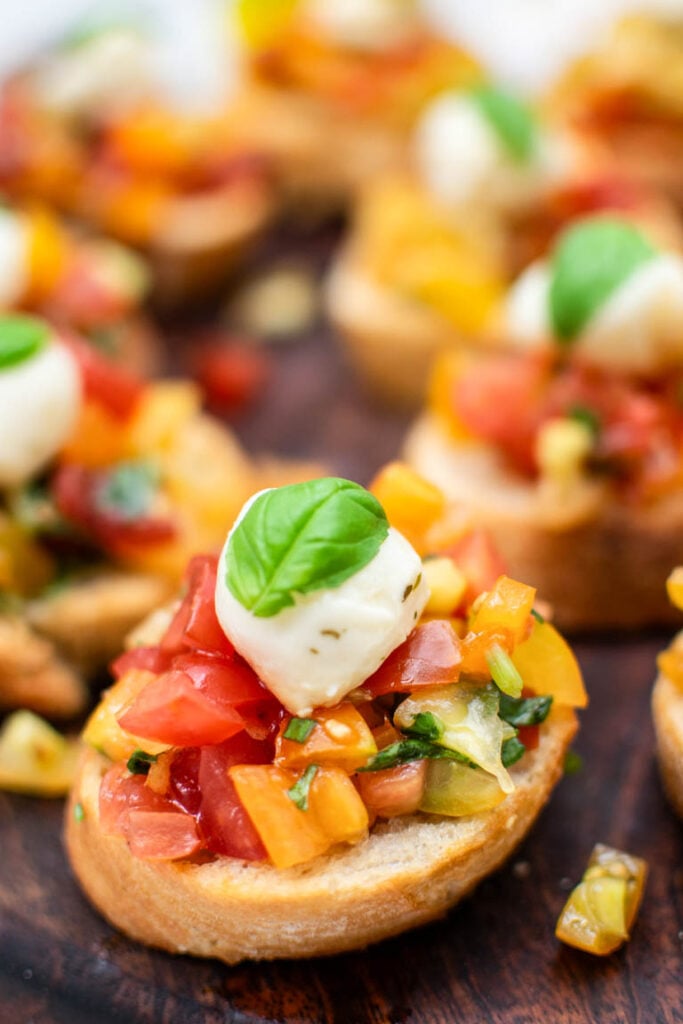 Caprese Bruschetta topped with cherry tomatoes, mozzarella pearls and fresh basil