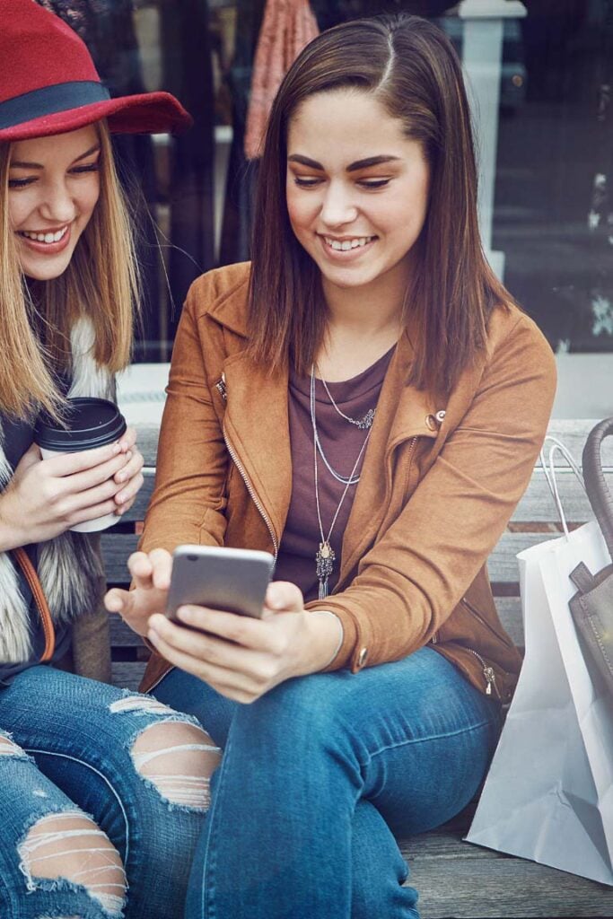 two young girls checking discount codes on mobile phones