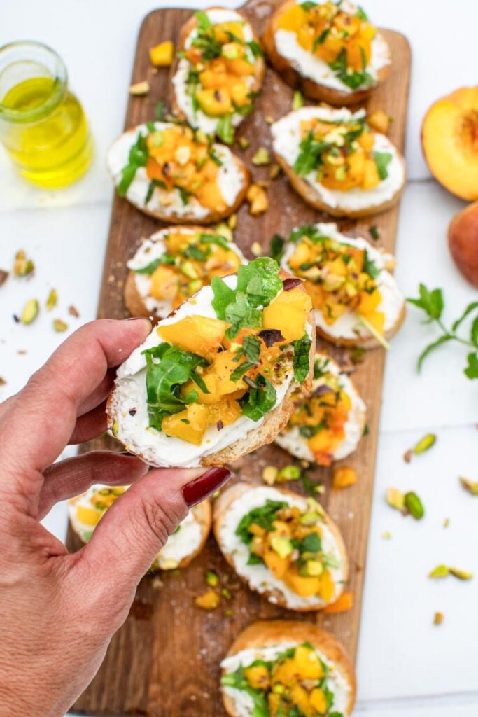 Assembled peach bruschettas drizzled with olive oil and black pepper