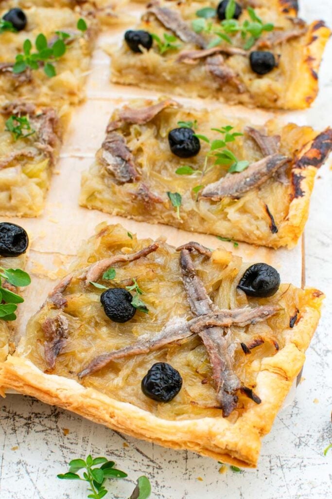 Sliced pissaladière showing caramelised onions, olives and puff pastry