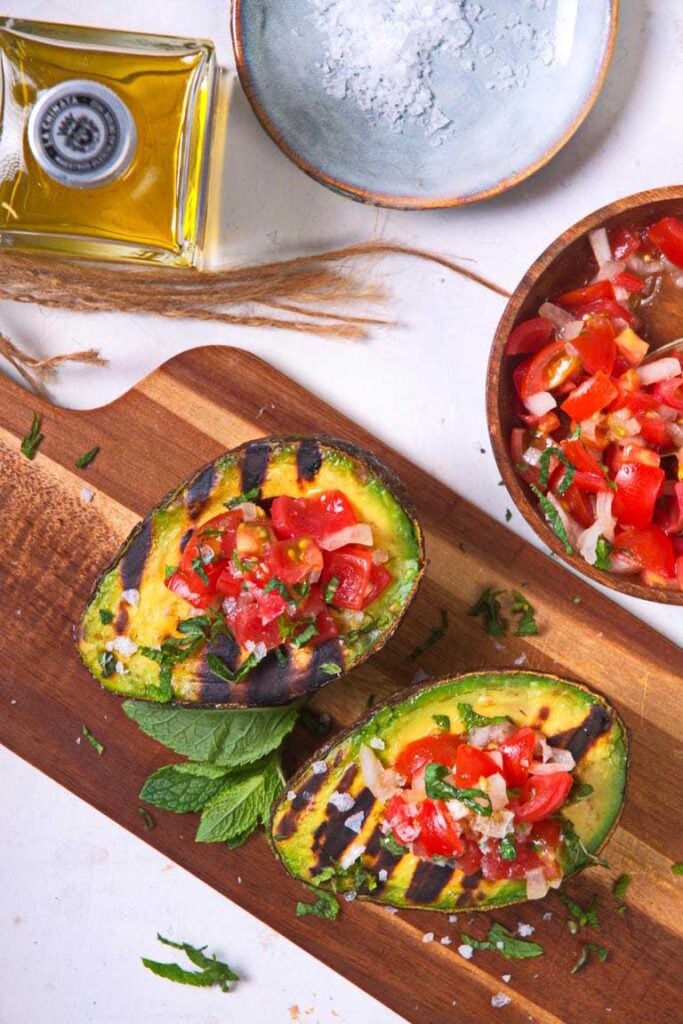 grilled stuffed avocado on wooden board