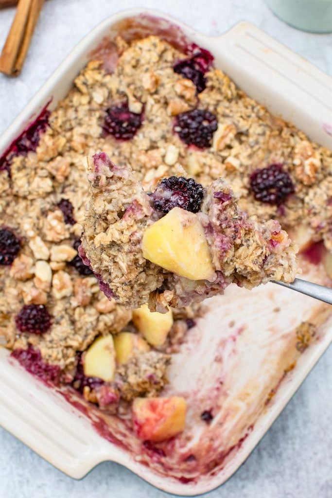 apple and blackberry in spoon with oatmeal in background