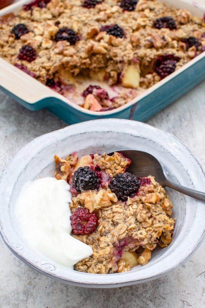 Apple & Blackberry Baked Oatmeal in a bowl with yoghurt and spoon