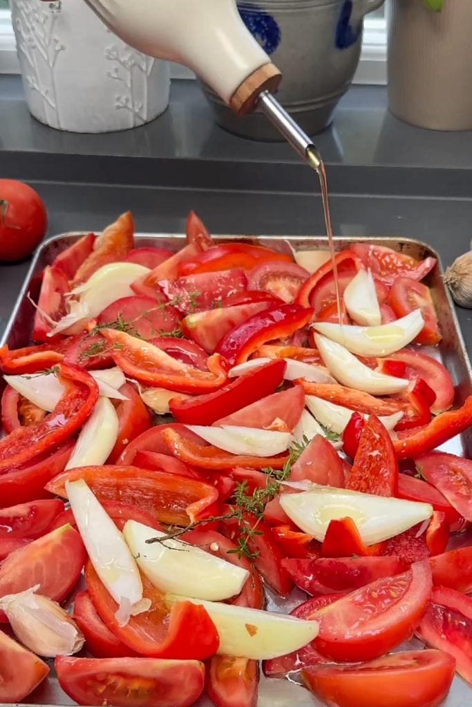 Drizzling tomatoes and red pepper with olive oil