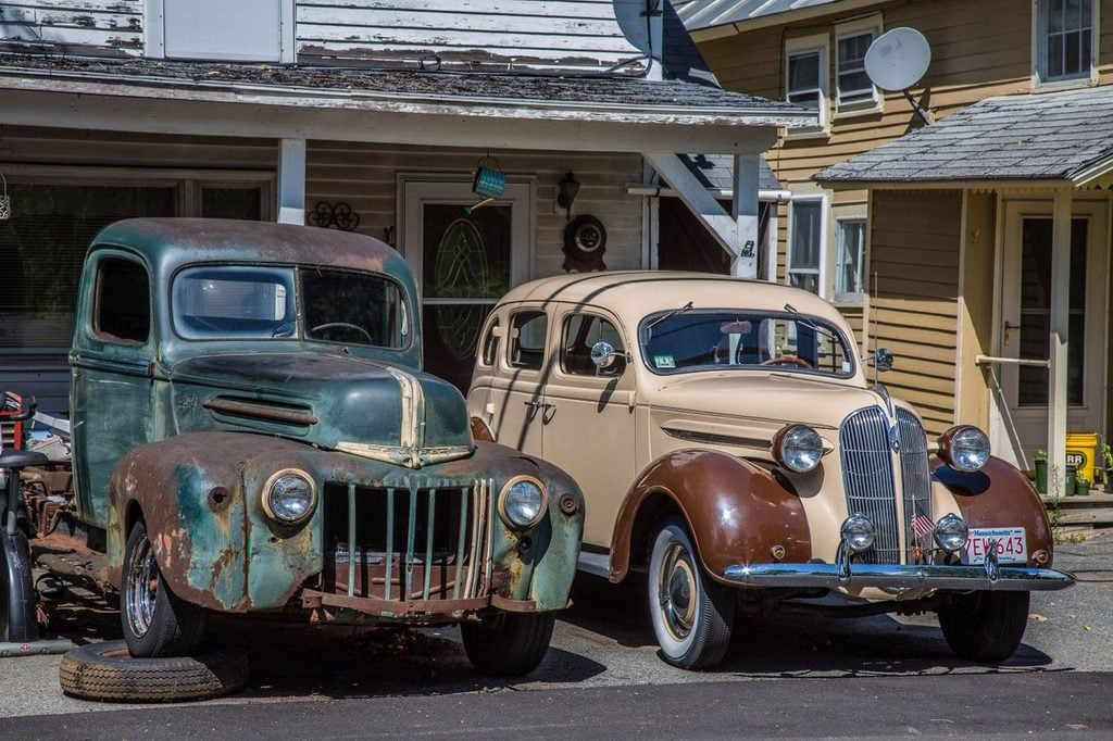 Really old cars parked in front of shop in small town
