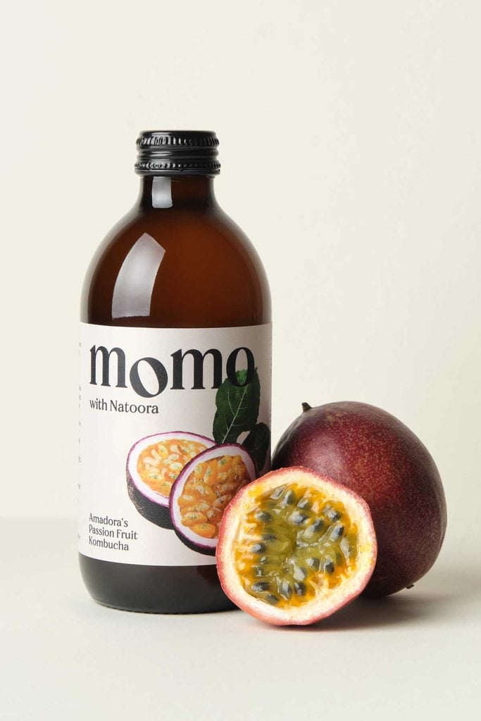 MOMO organic passion fruit kombucha bottle surrounded by fresh passion fruit