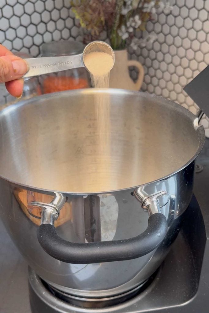 Flour being poured into a stainless steel mixing bowl to make the pumpkin bread dough