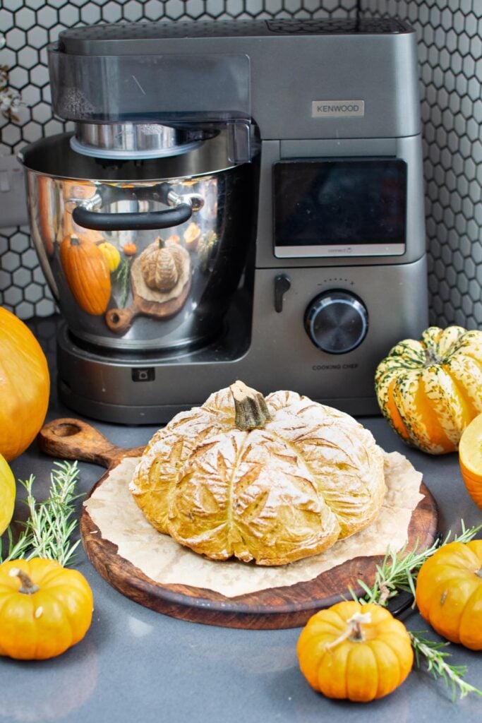 Pumpkin shaped bread on a wooden board in front of a Kenwood Cooking Chef XL, with pumpkins and rosemary