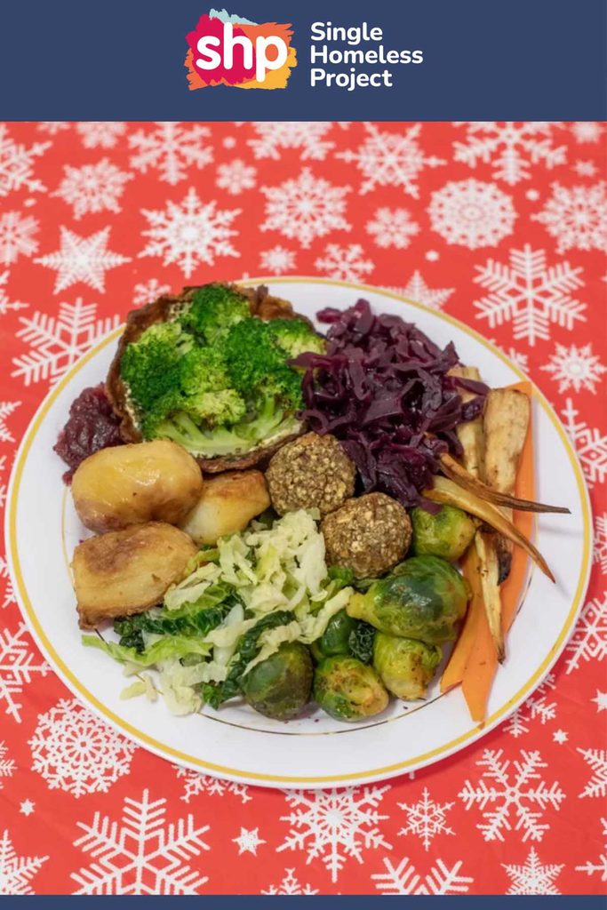 Vegan Christmas dinner with nut roast balls, roast potatoes, red cabbage, broccoli and sprouts on a festive tablecloth
