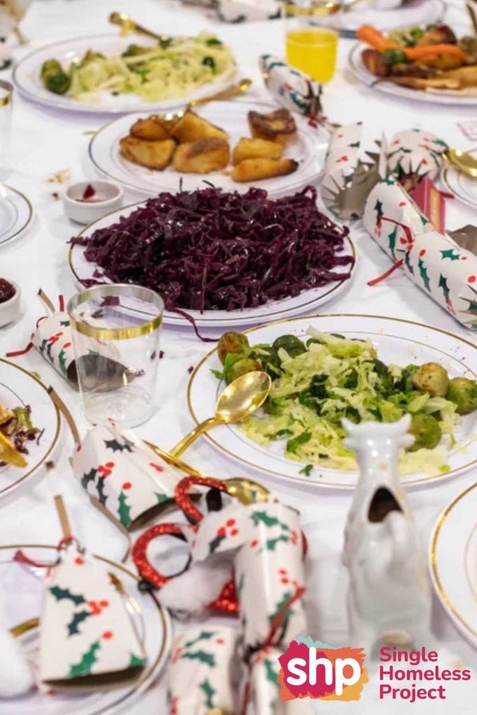 Festive table with red cabbage, roast potatoes, sprouts and Christmas crackers at a Single Homeless Project dinner