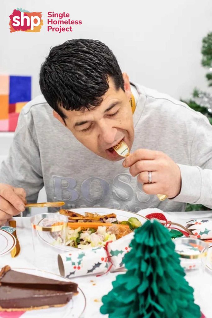 Man tucking into a vegetarian Christmas dinner at a Single Homeless Project festive meal