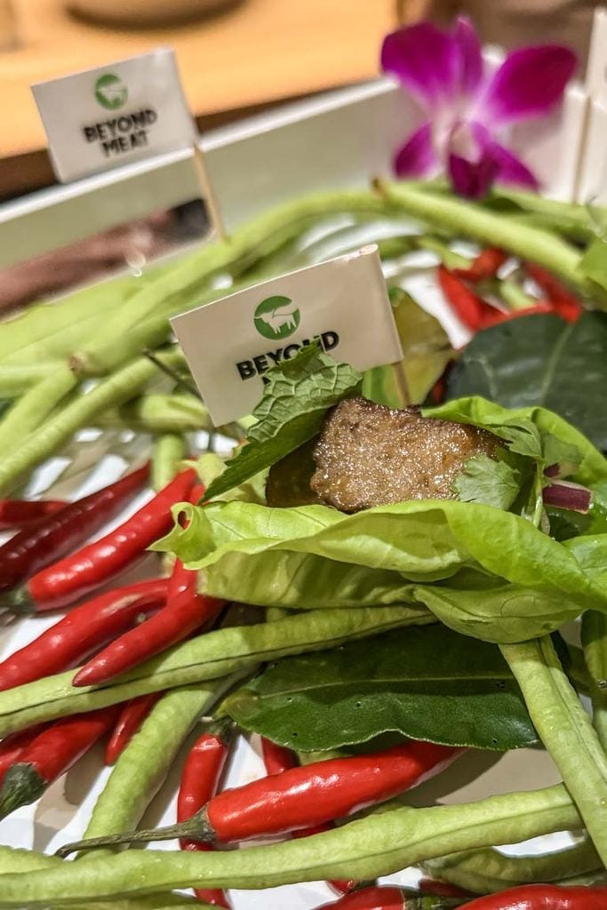 Beyond Meat Thai vegan canapé on a lettuce leaf, surrounded by red chillies and long beans
