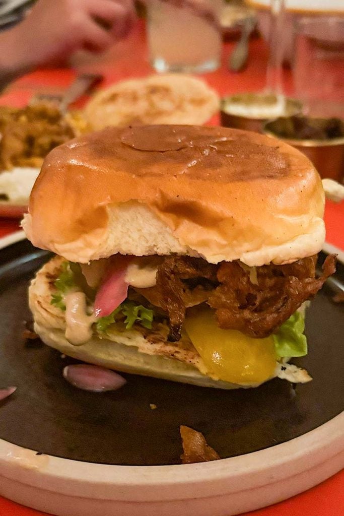 Trinco banana blossom burger with pol sambol, rassam onions, garlic yoghurt and pickles