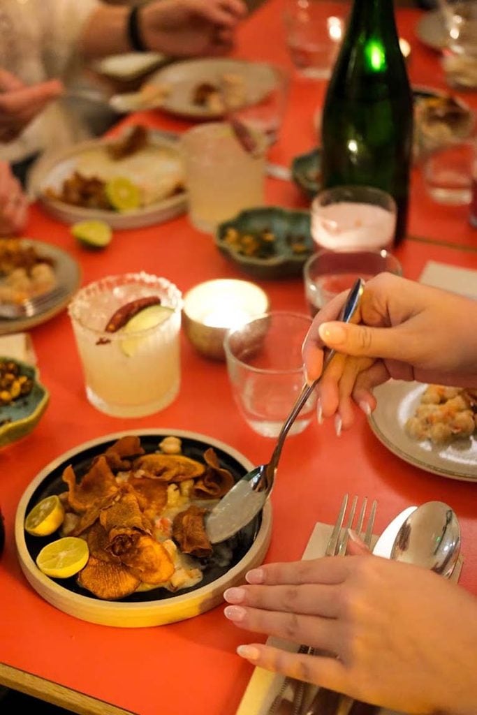 Shared dishes and cocktails on a red table at Trinco East Dulwich