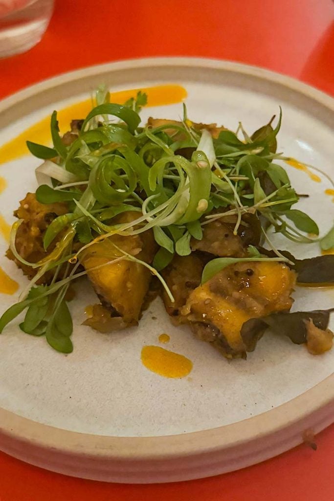Vazhakki varuval, fried plantain with green chilli, topped with fresh herbs at Trinco